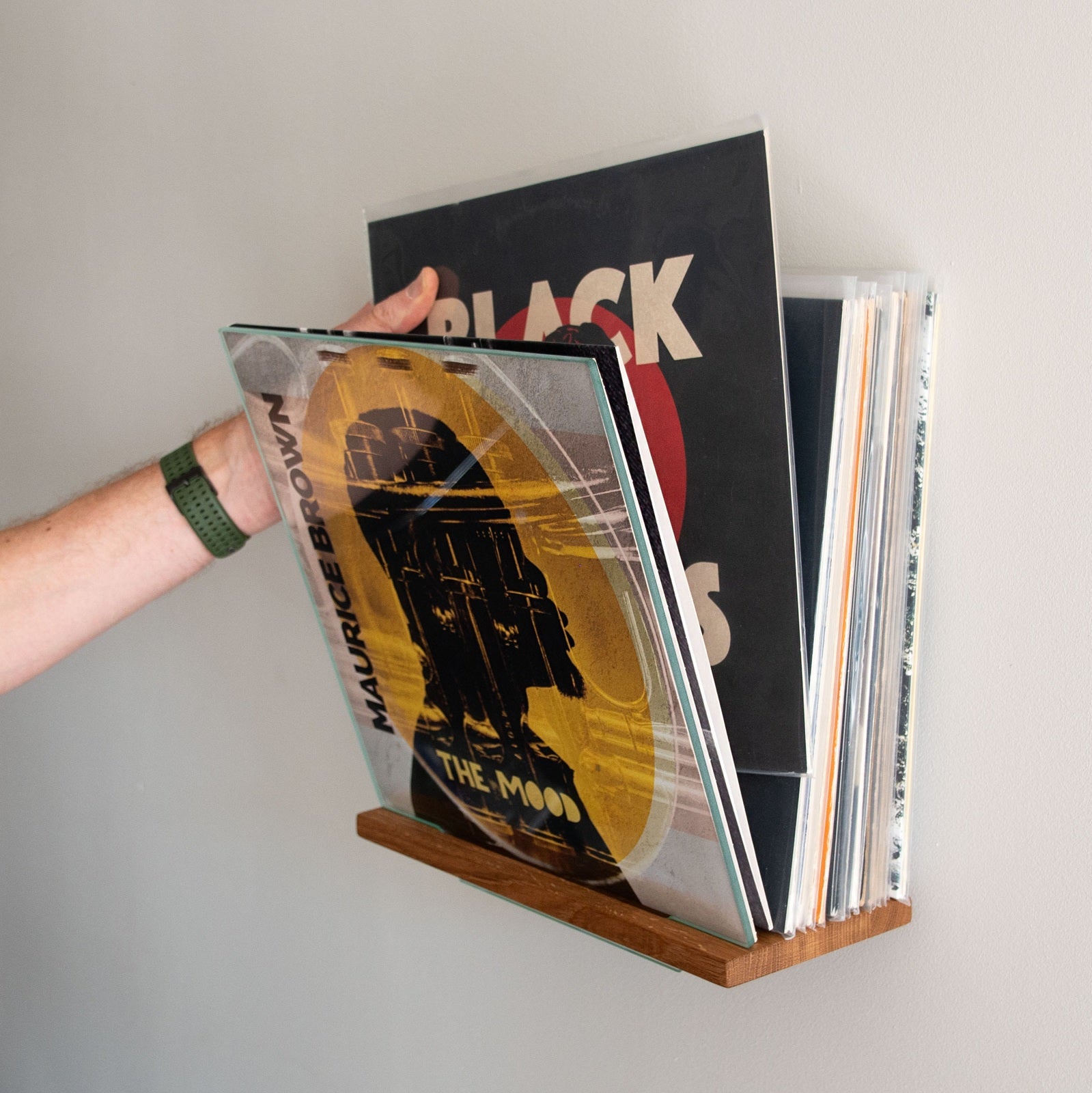 Platenliefhebber bladert door lp’s in het Display MULTI wandrek met praktische flip-functie